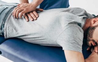 Chiropractor treating patient lying facedown on a table. - Chiropractor vs Physical Therapist
