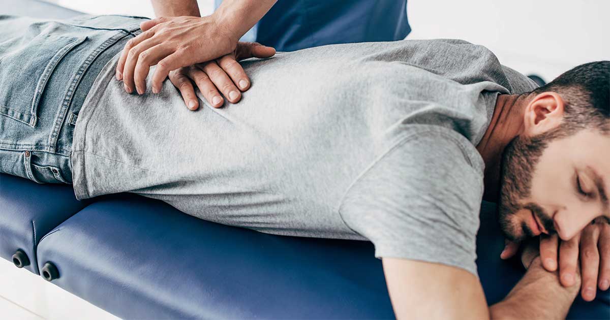 Chiropractor vs Physical Therapist Chiropractor treating patient lying facedown on a table. - Chiropractor vs Physical Therapist